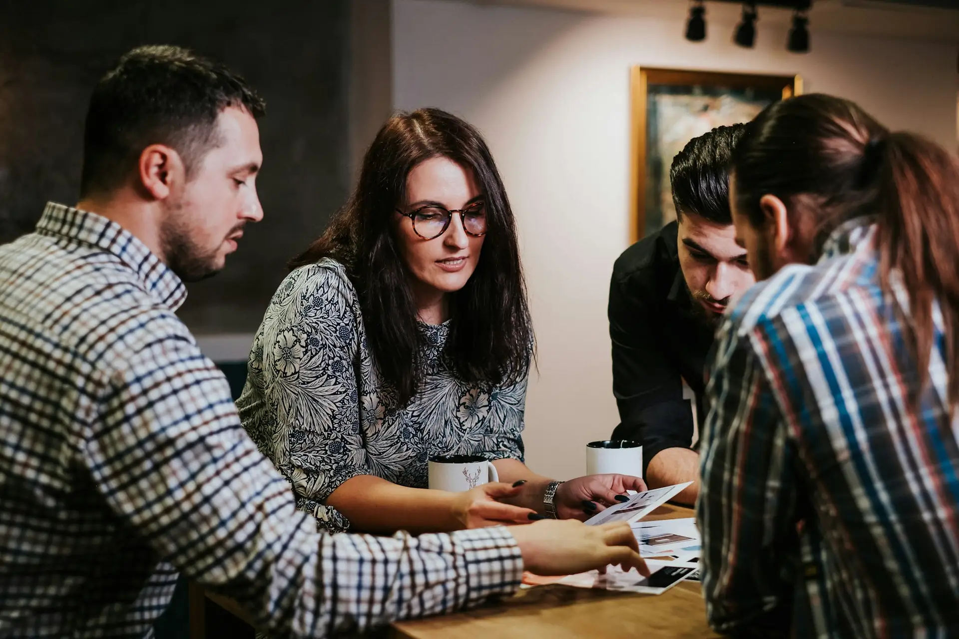 Four colleagues around a table going through printed documents together