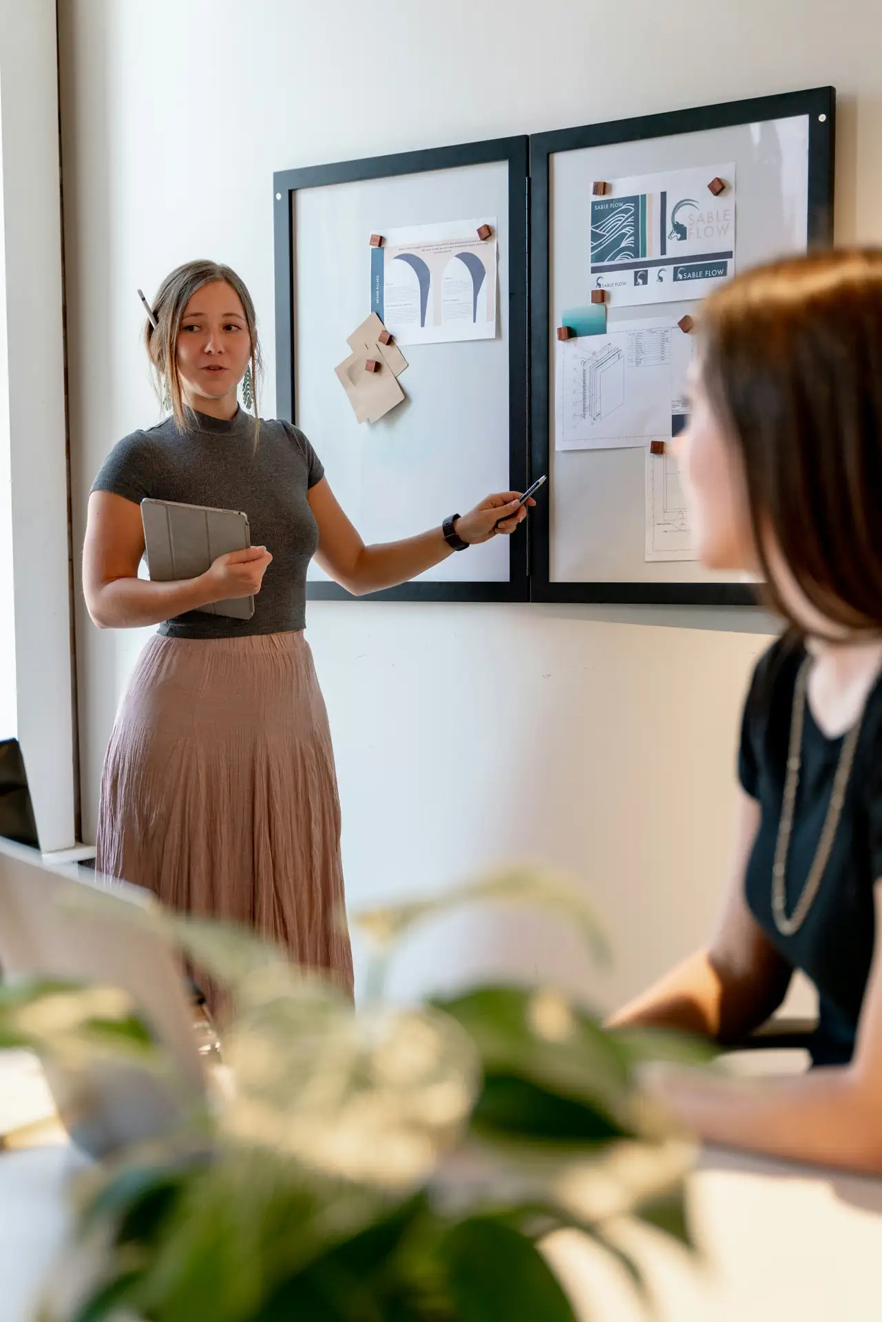 A colleague presenting a plan on a whiteboard to a small group in a bright meeting room