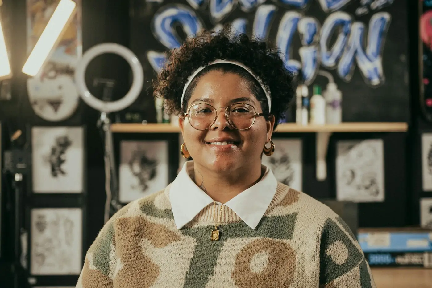 An illustrator smiling in her studio, surrounded by her own work