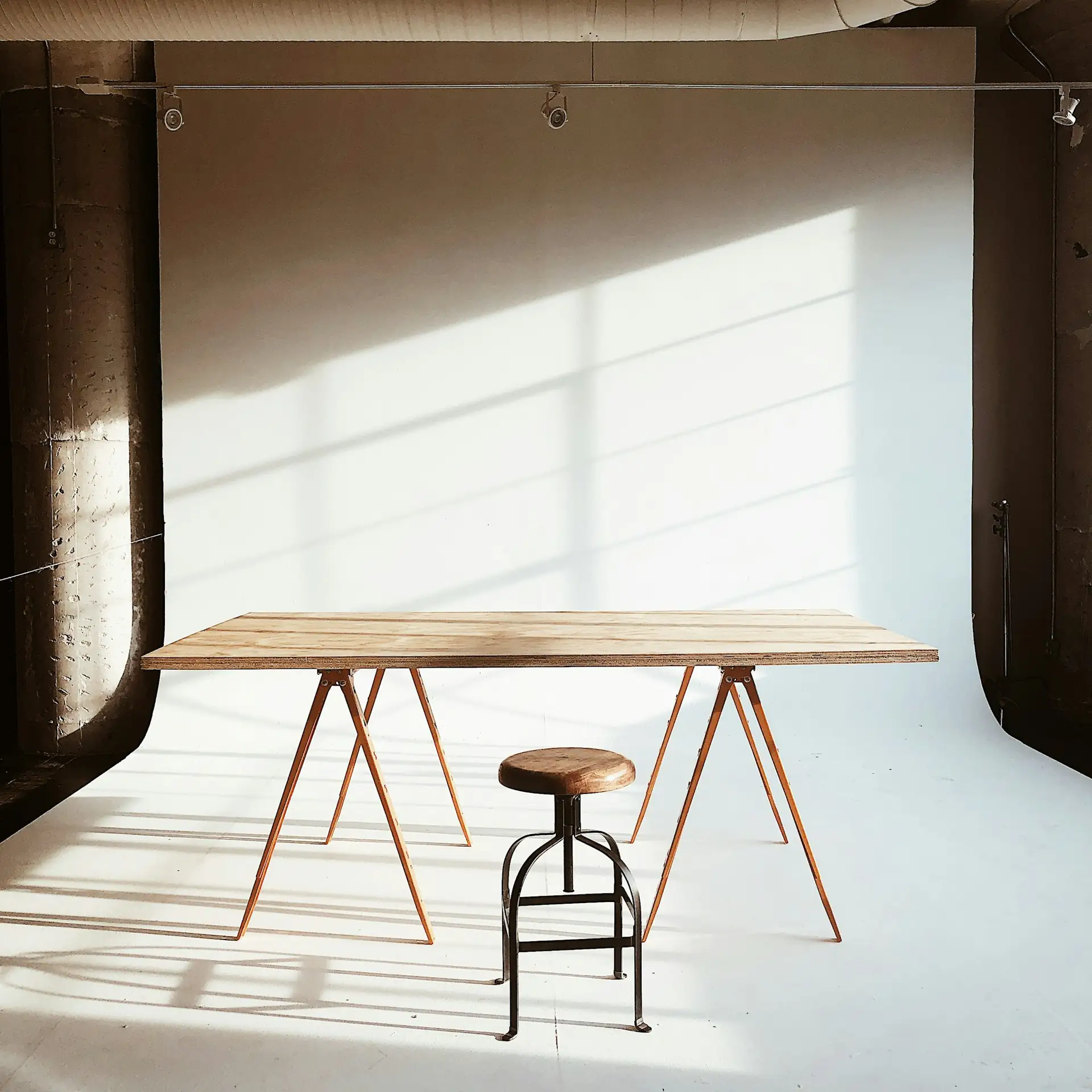 Un tavolo di legno a cavalletti in uno studio vuoto e soleggiato