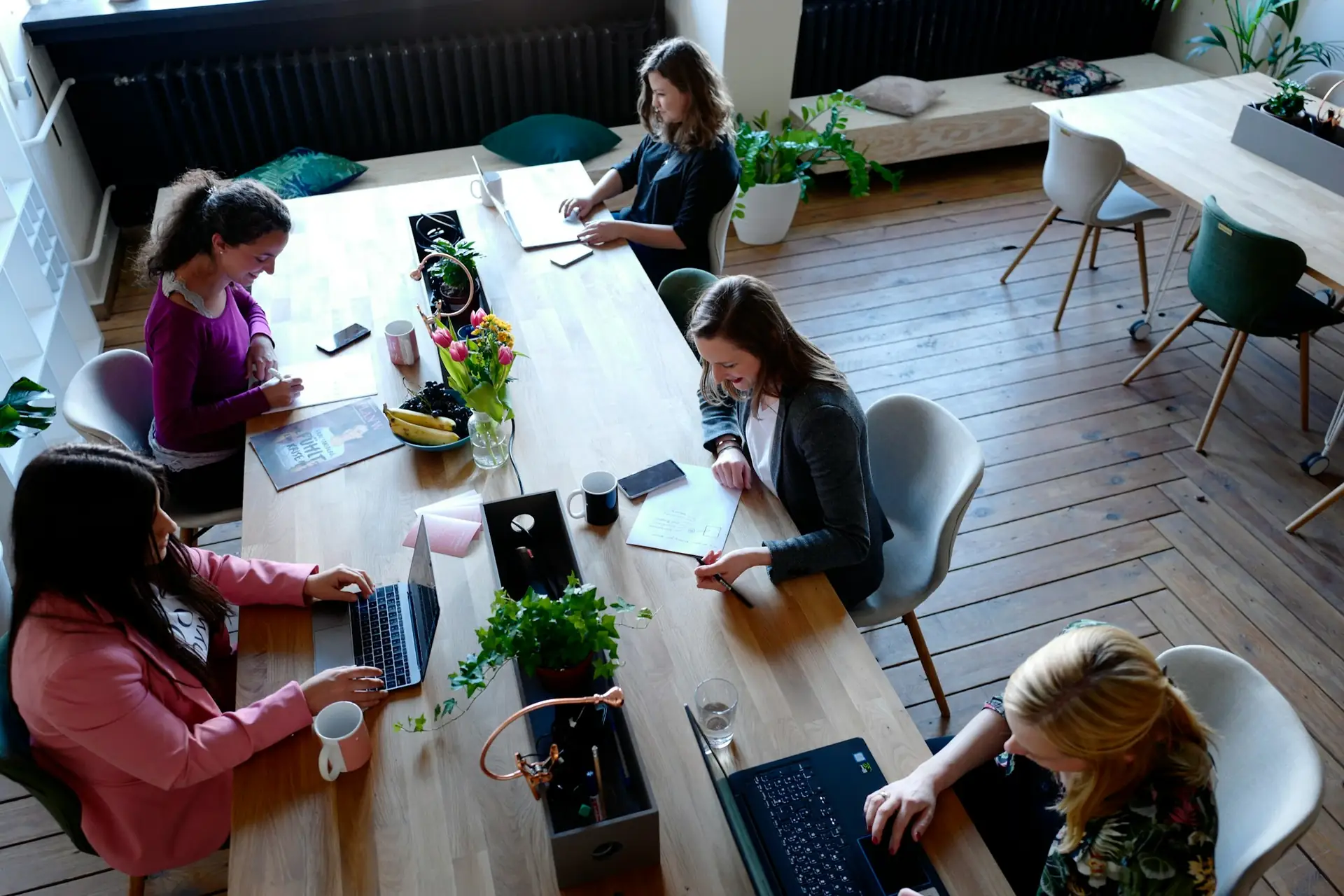 A large team working at long shared tables in a bright open office, seen from above
